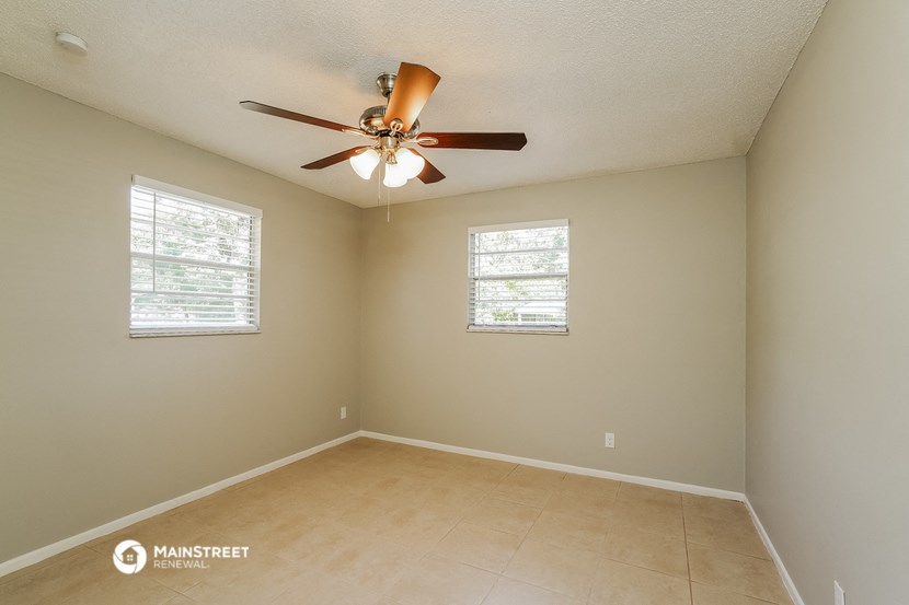 an empty room with a ceiling fan and two windows