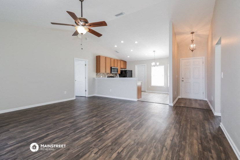 the living room and kitchen of an empty house with a ceiling fan