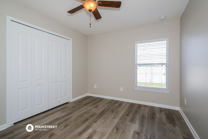 the spacious living room with wood flooring and a ceiling fan