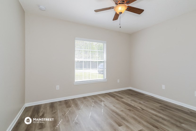the spacious living room with hardwood floors and a ceiling fan