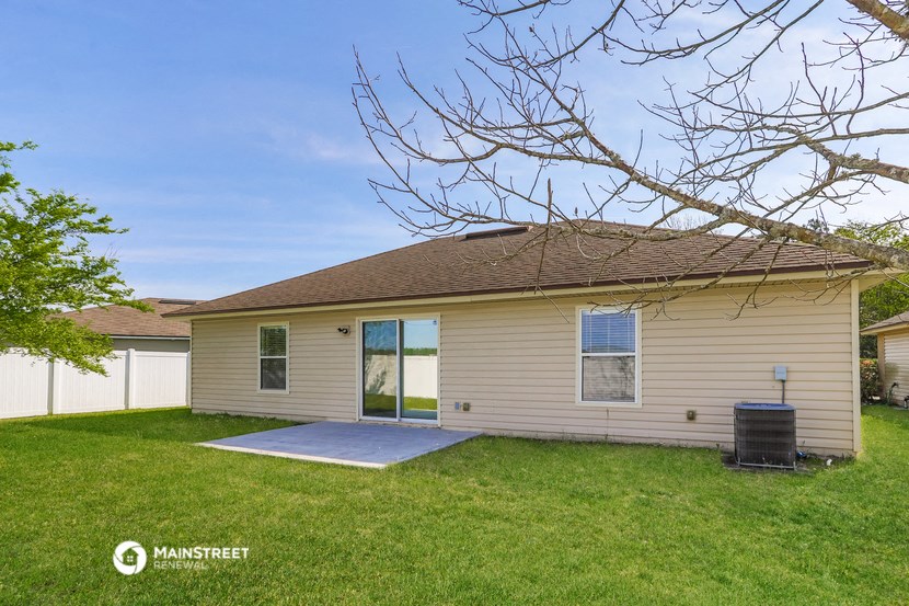 a small tan house with a yard and a white fence