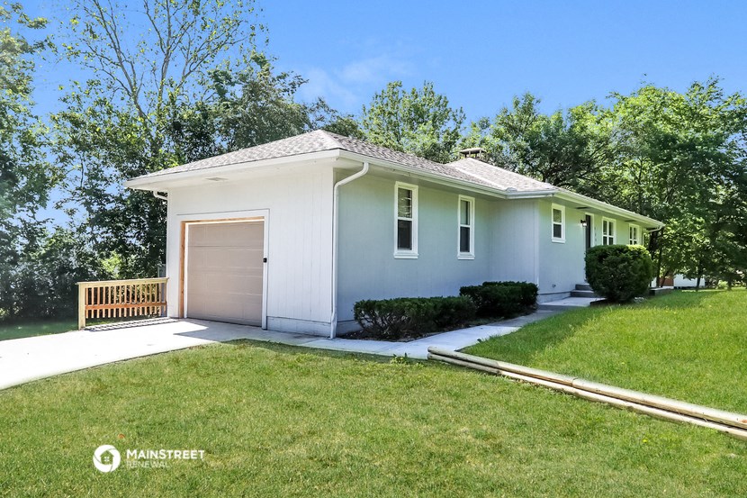 a small white house with a driveway and a garage door
