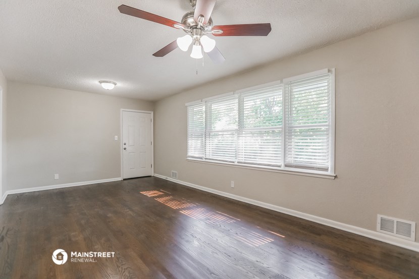 an empty living room with a ceiling fan and a window