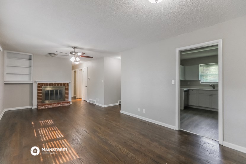 an empty living room with a fireplace and a ceiling fan