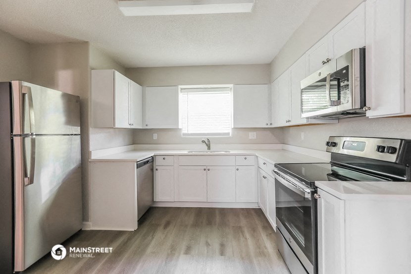an empty kitchen with white cabinets and stainless steel appliances