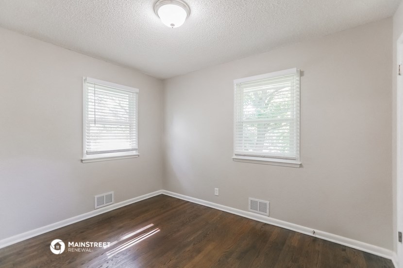 the spacious living room with hardwood flooring and two windows