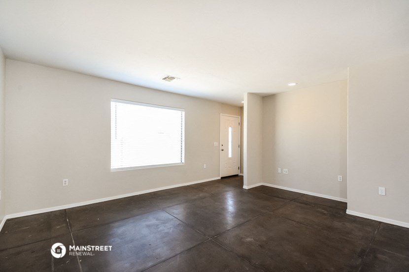 the living room of a house with a large window and concrete floors