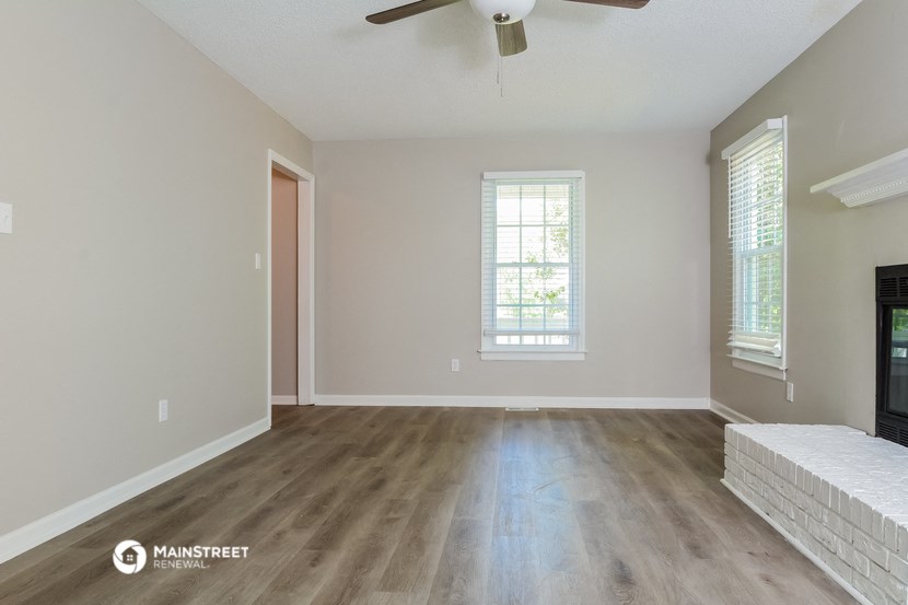 an empty living room with wood floors and a ceiling fan