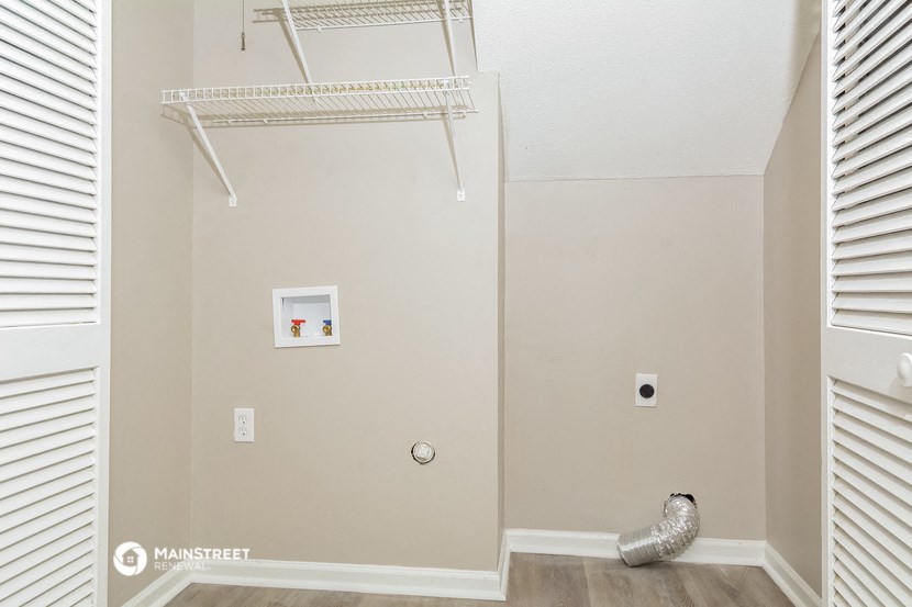 a walk in closet with a white closet shelf and a closet door with a closet