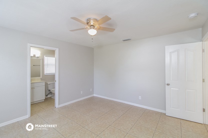 an empty living room with a ceiling fan and a bathroom
