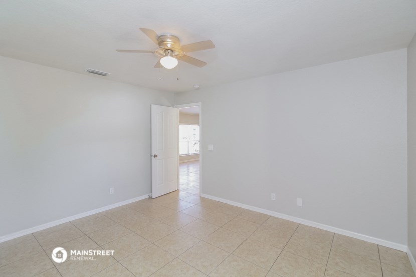 the spacious living room with ceiling fan and tile flooring