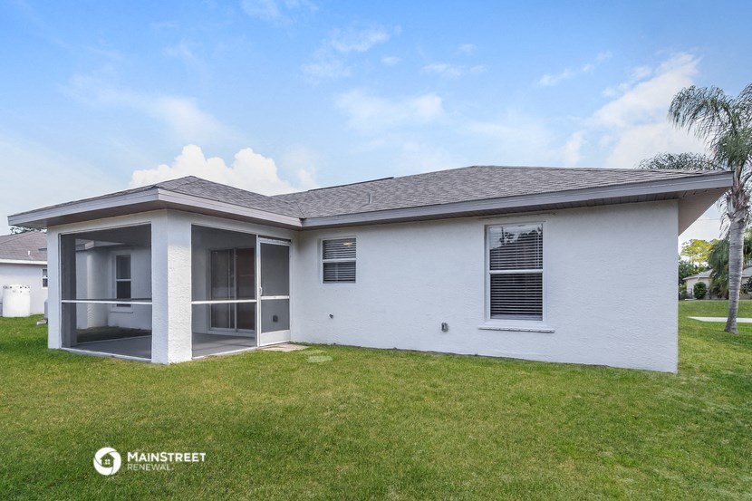 a white house with a lawn and a palm tree