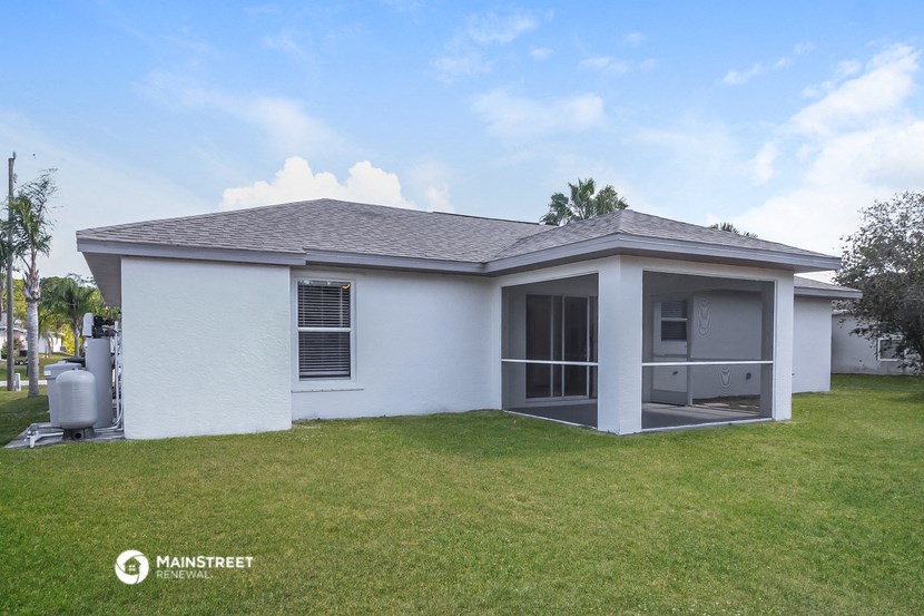 a small white house with a lawn and a blue sky