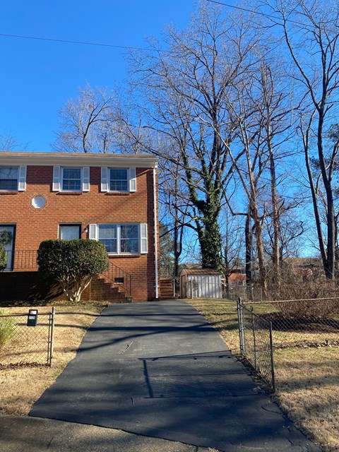 A residential building with a driveway and bare trees in the background.