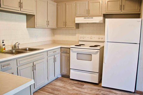 A white refrigerator is in a kitchen with white appliances.