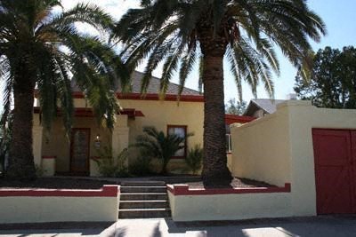 A house with a red door and a palm tree in front.