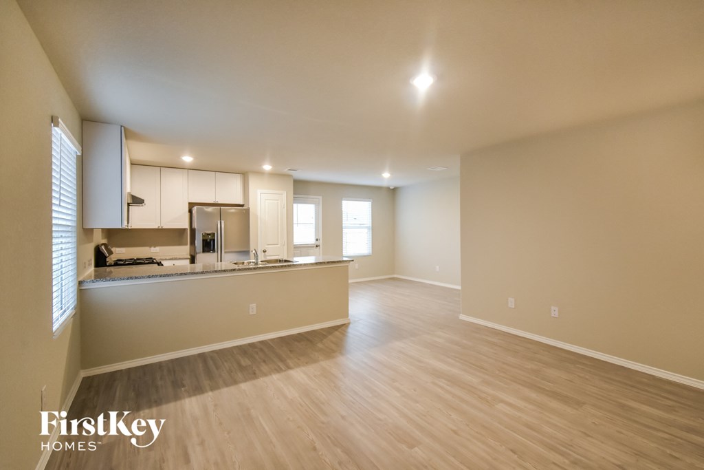 an empty living room and kitchen with wood flooring