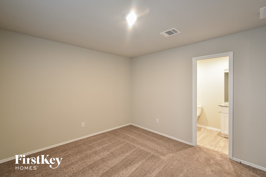 a bedroom with a carpeted floor and a door to a bathroom