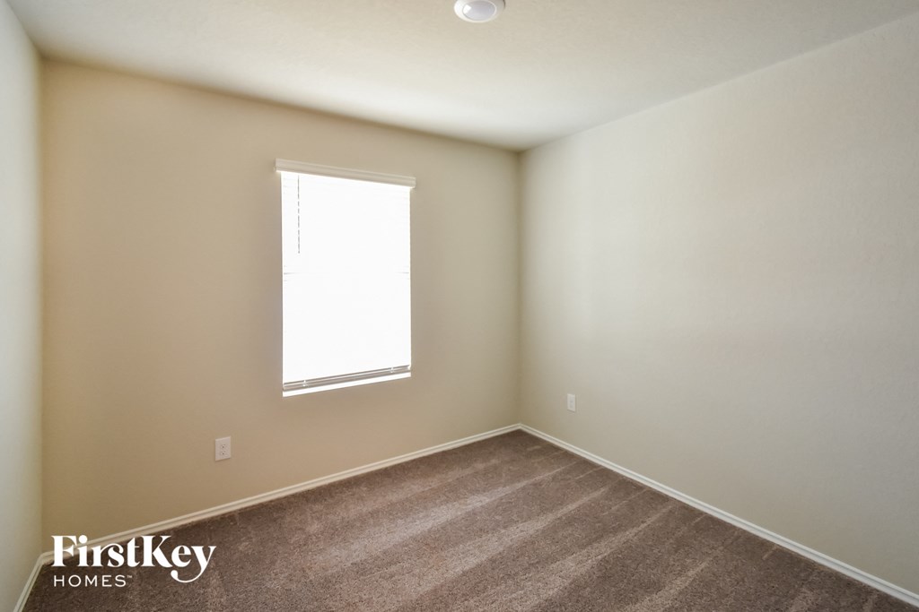 a bedroom with a window and a carpeted floor