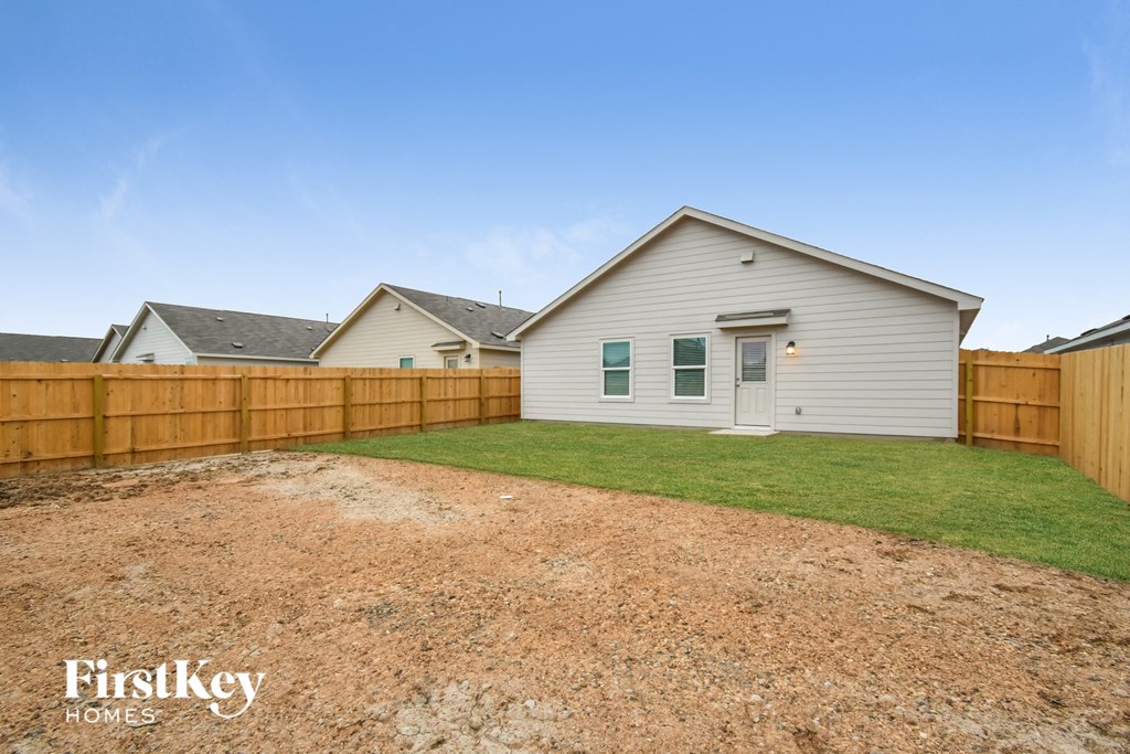 a backyard with a white house and a wooden fence