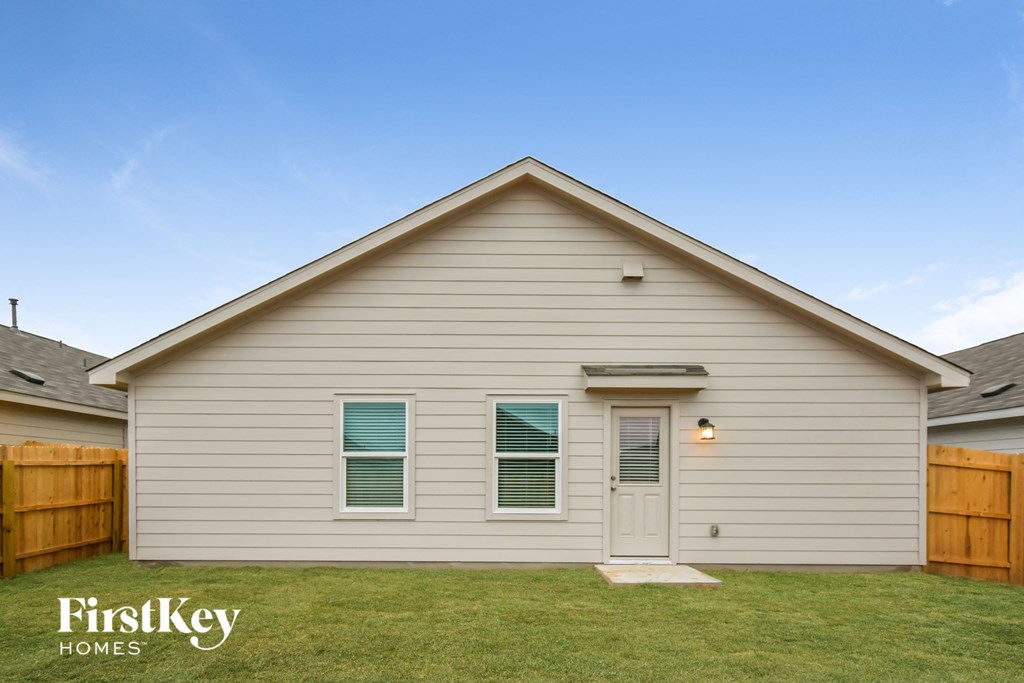 the outside of a house with a lawn and a wooden fence