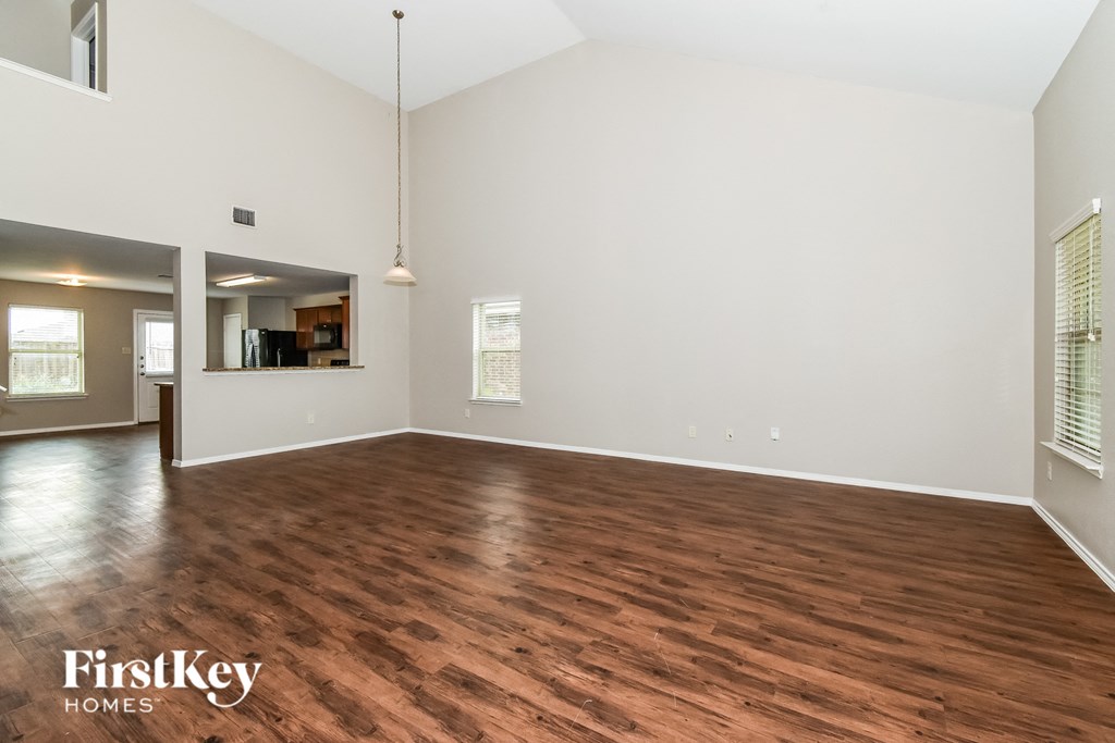 the living room and dining room with wood flooring and white walls