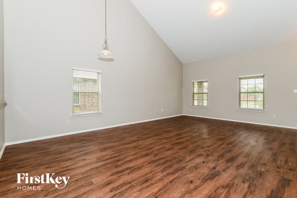 the spacious living room with wood floors and white walls
