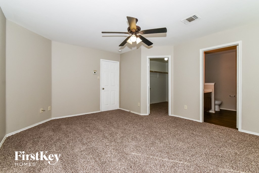 a bedroom with a ceiling fan and a door to a bathroom
