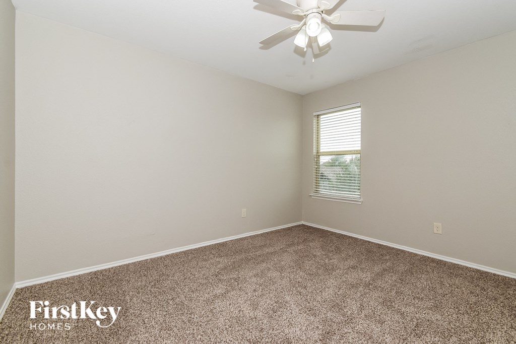 the spacious living room with carpeting and a ceiling fan