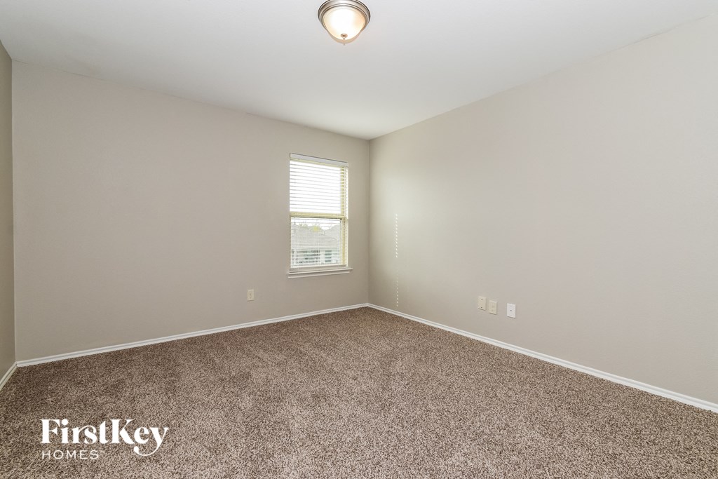 the spacious living room with carpeting and a window