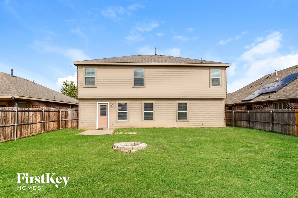the back of a house with a yard and a wooden fence
