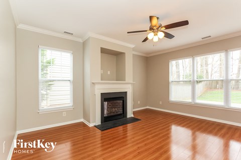 A living room with a fireplace and a ceiling fan.