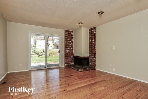 A room with wooden floors and a brick fireplace.