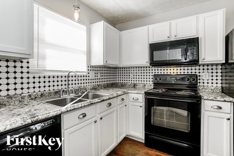 A kitchen with black and white tiles and a black stove top oven.