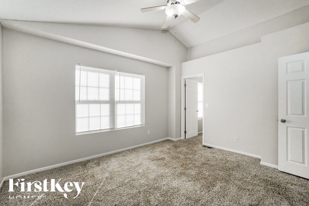 A spacious room with a carpeted floor and a ceiling fan.
