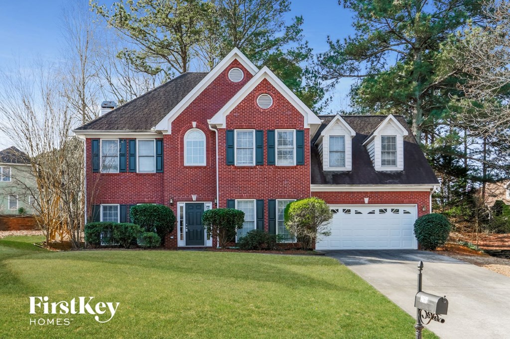 a red brick house with a white garage door and a lawn