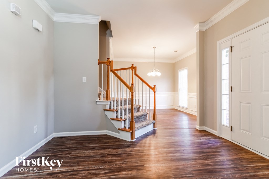 the foyer and entryway of a home with white walls and wood floors