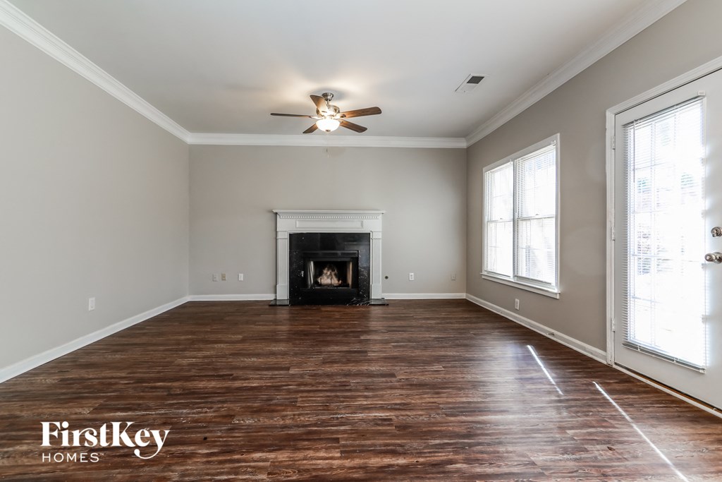 an empty living room with a fireplace and a ceiling fan