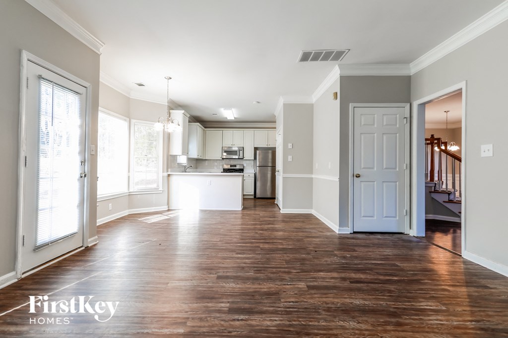 an empty living room with a kitchen in the background
