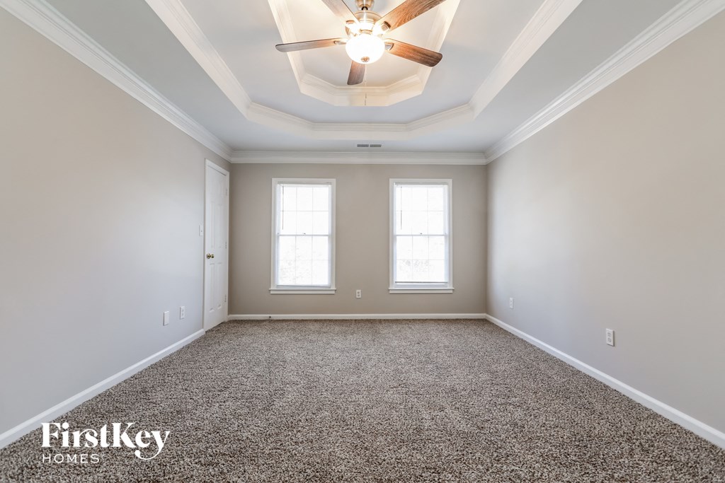 a empty room with a ceiling fan and two windows