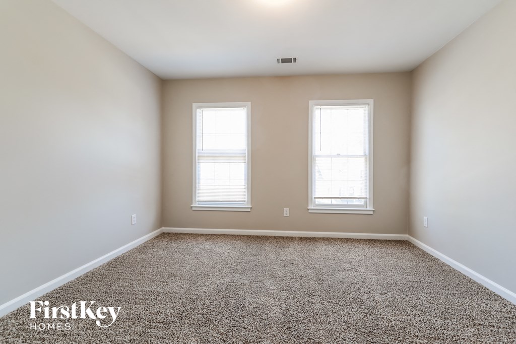 a empty room with two windows and a carpeted floor