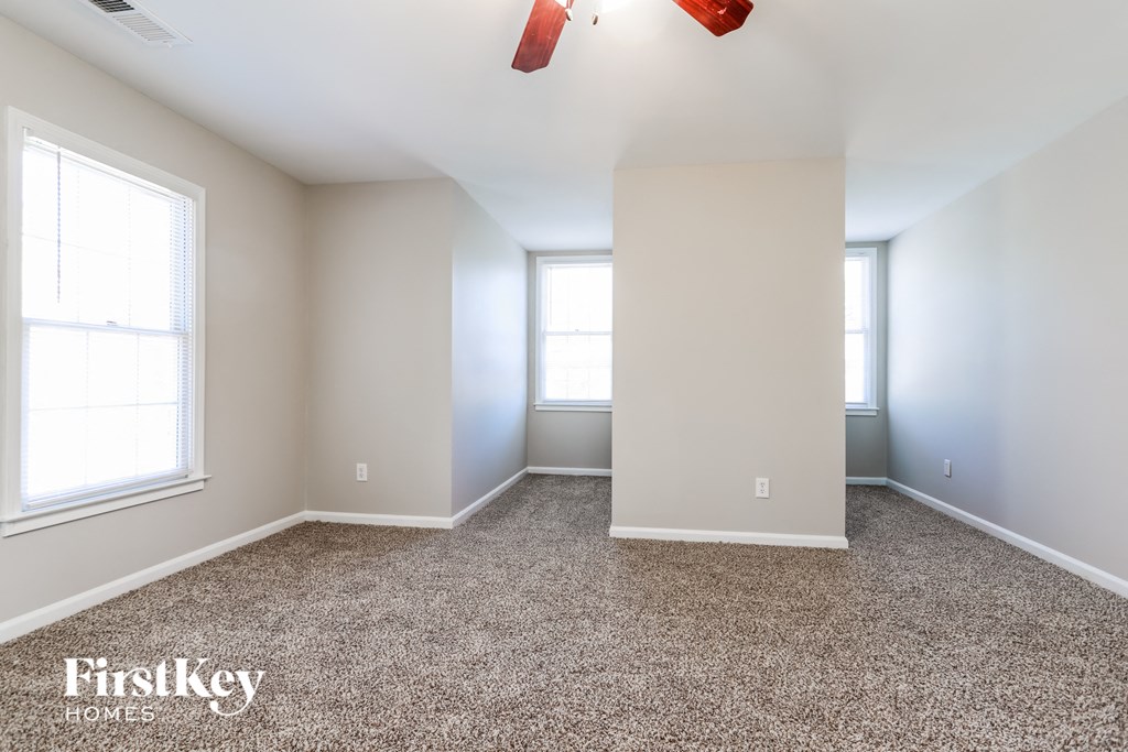 a empty room with carpet and two windows