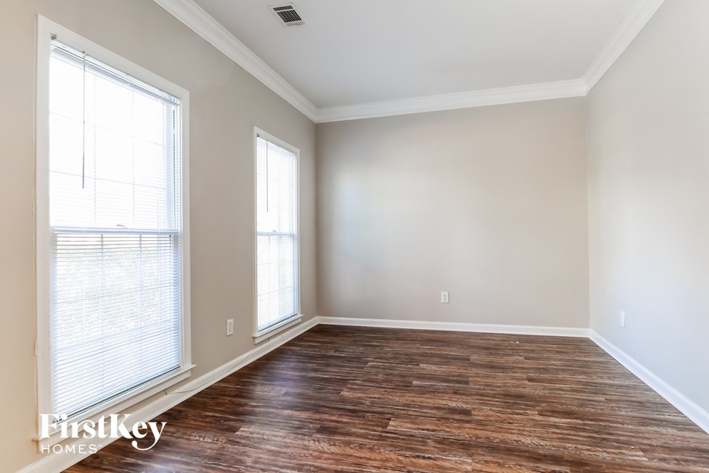 an empty room with wood flooring and two windows