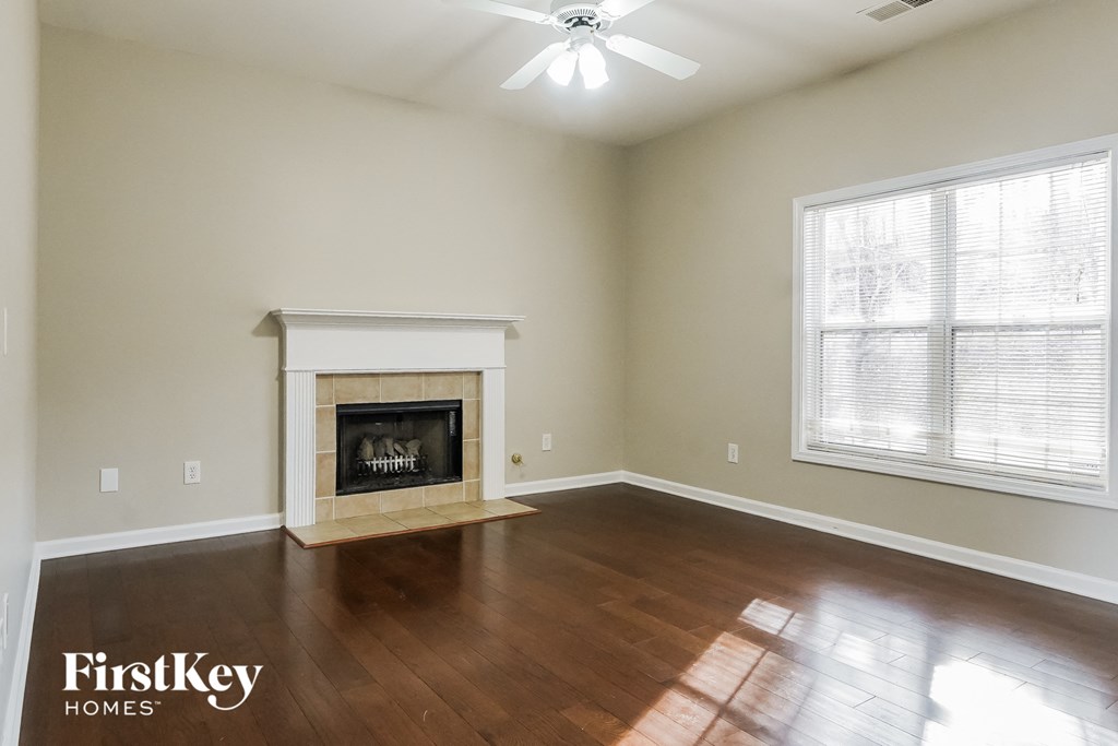 A spacious living room with a fireplace and a ceiling fan.