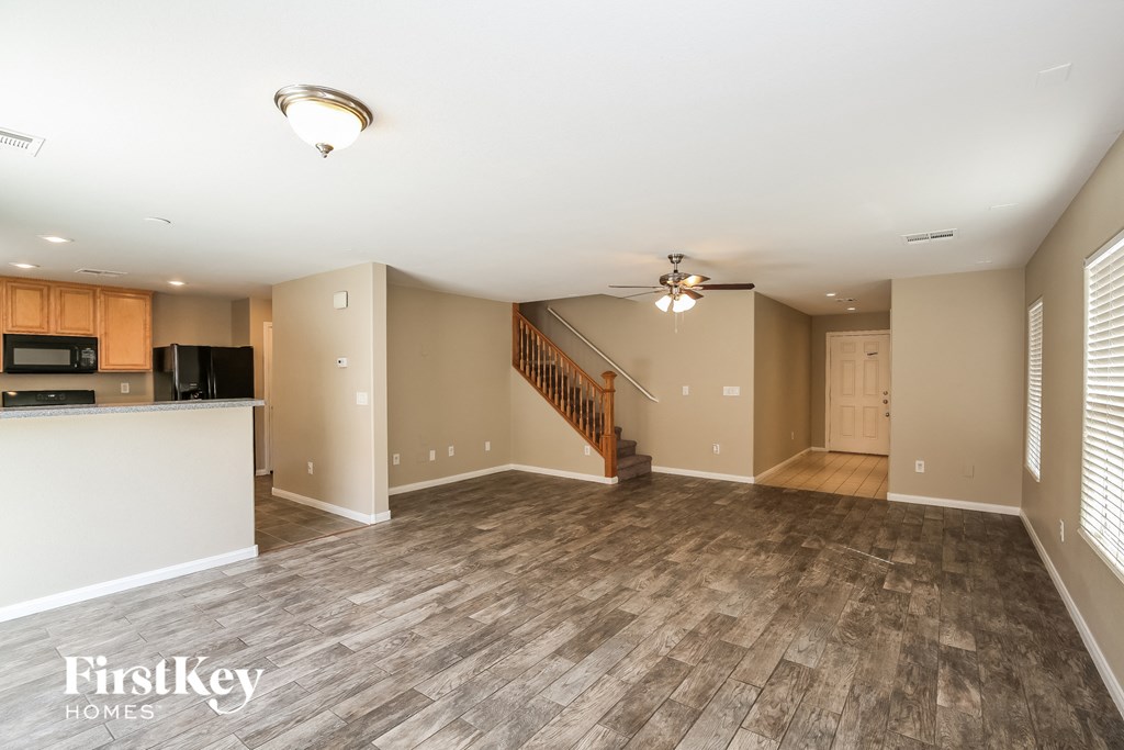 A spacious living room with wood flooring and a staircase leading to the upper level.
