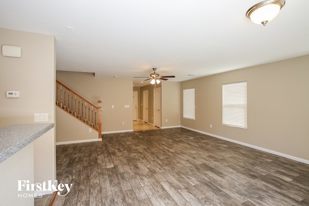 A spacious room with wooden flooring and a ceiling fan.