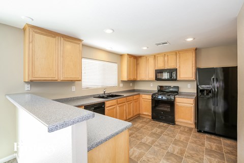 A kitchen with wooden cabinets and black appliances.
