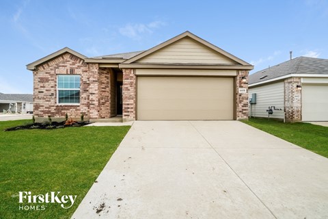 A house with a garage door and a driveway in front of it.