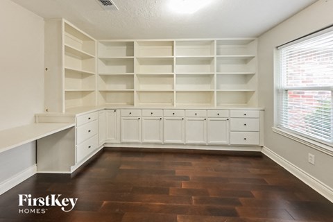 a kitchen with white cabinets and shelves and a large window