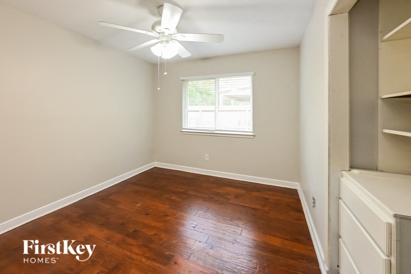a bedroom with a hard wood floor and a ceiling fan
